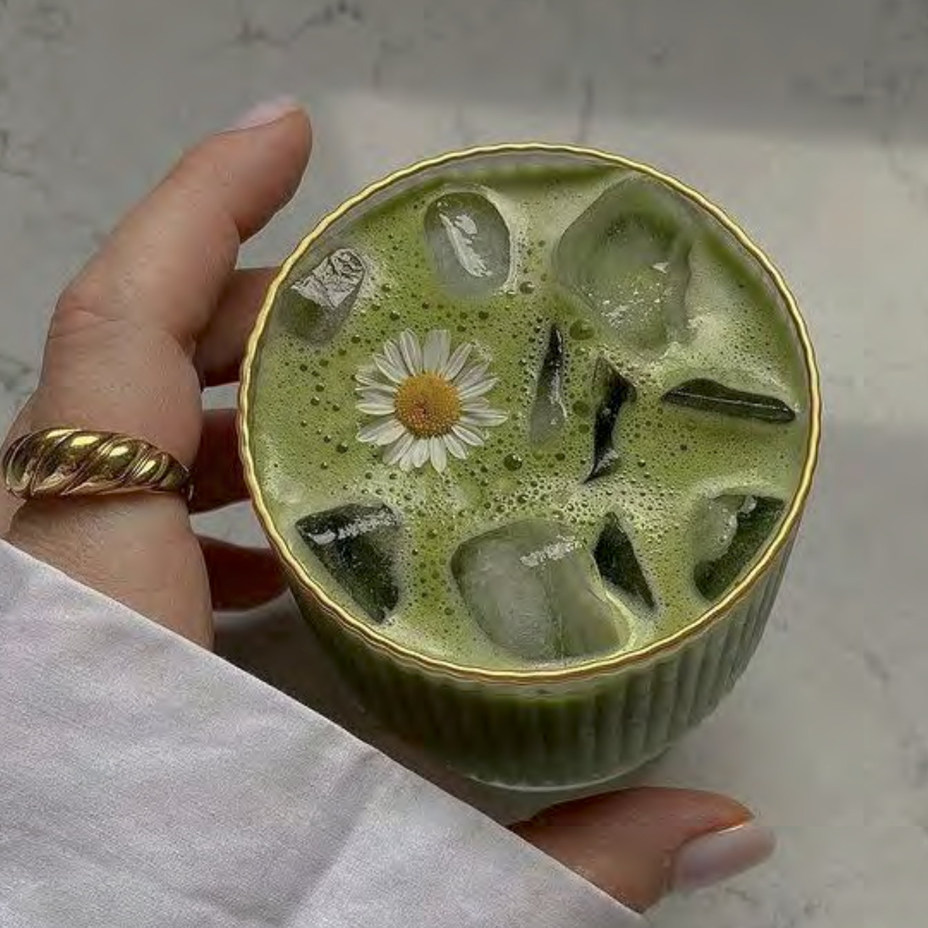Overhead shot of matcha powder in a bowl, surrounded by traditional Japanese tea tools on a neutral background.
