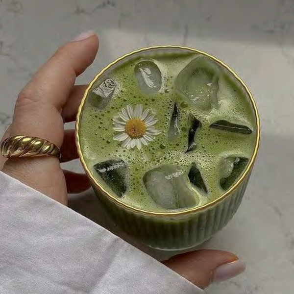Overhead shot of matcha powder in a bowl, surrounded by traditional Japanese tea tools on a neutral background.
